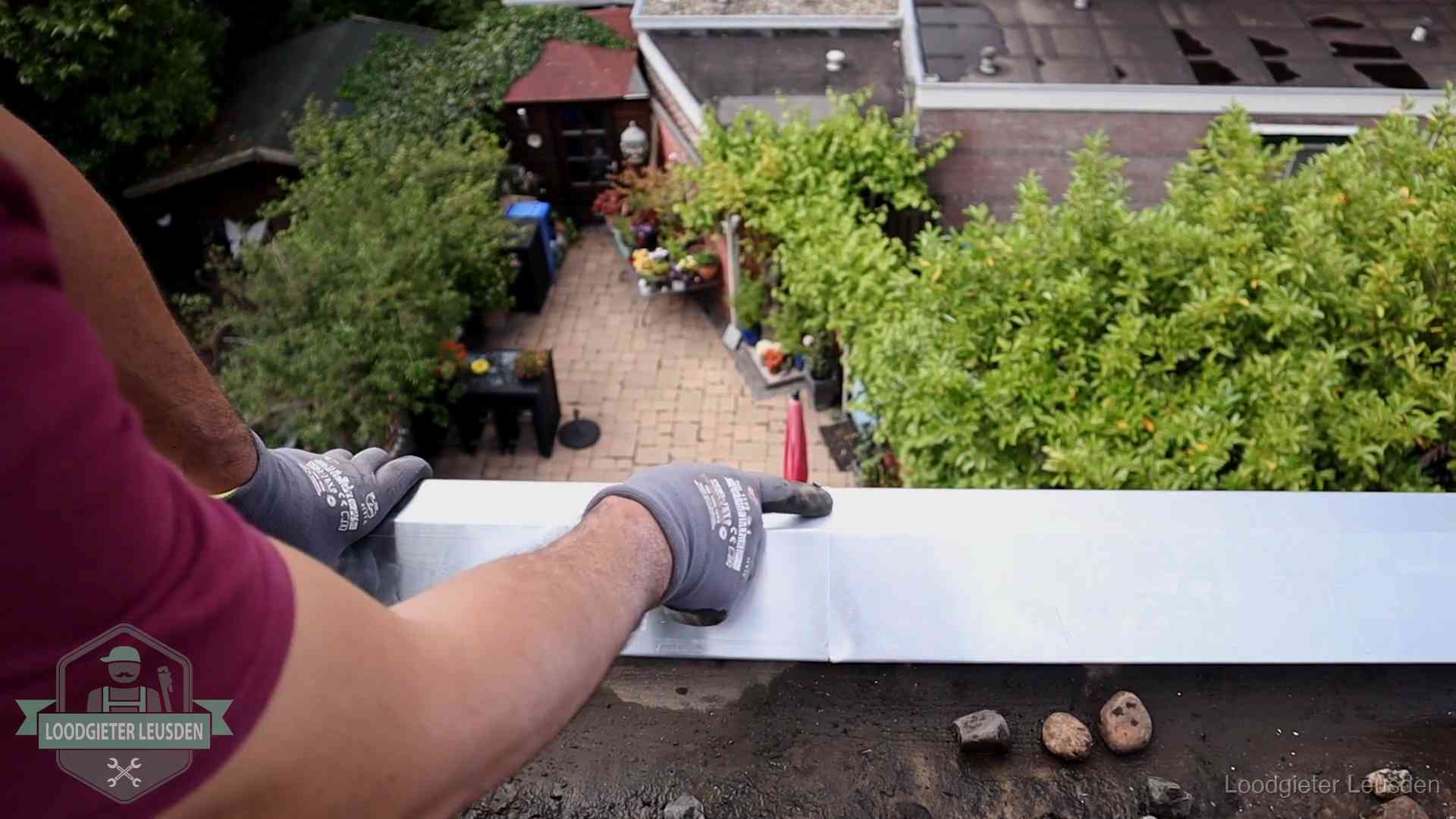 Vakman plaatst een daktrim op de dakrand van een woning in Leusden