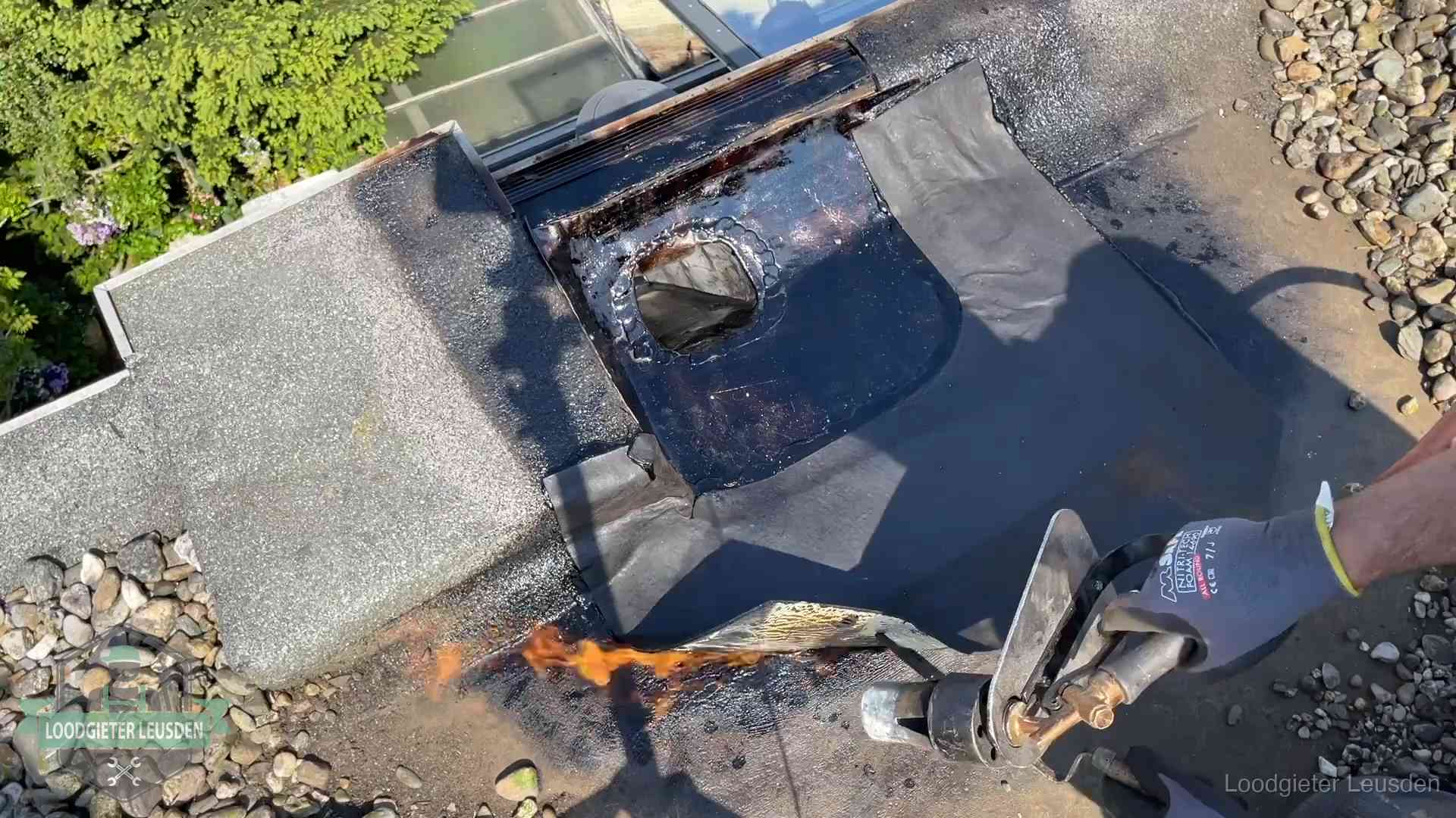 Dakdekker brandt bitumen rond een doorvoer tijdens een daklekkage-reparatie in Leusden