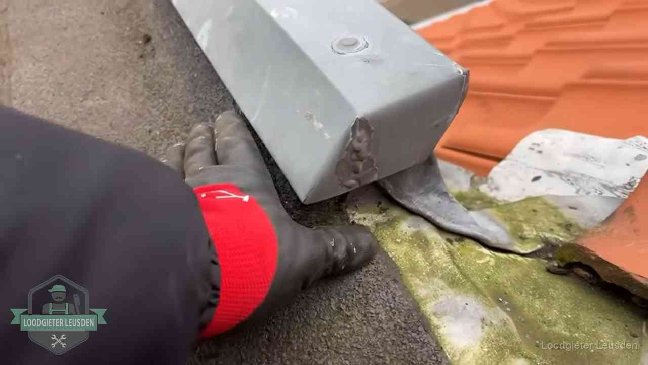 Controle van een zinken hemelwaterafvoer met loodslab bij dakpannen in Leusden