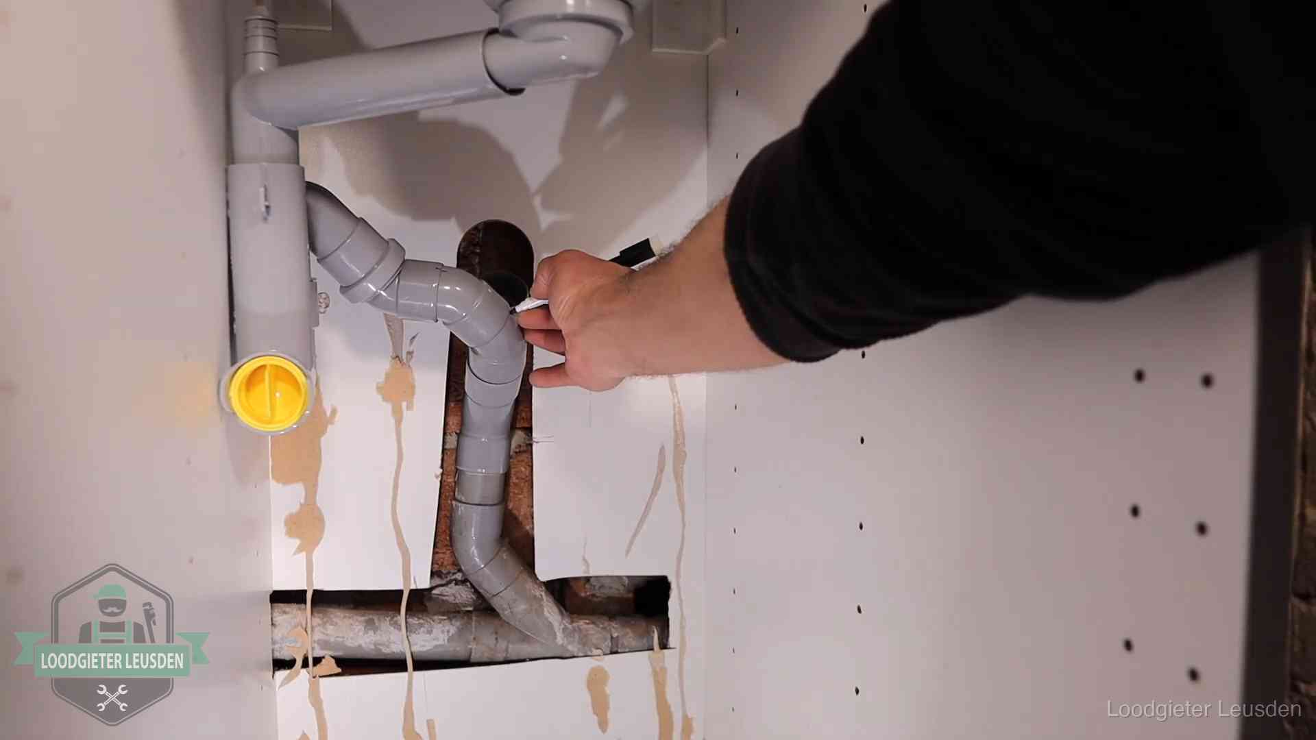 Loodgieter markeert een pvc-afvoerbuis onder een gootsteen in Leusden