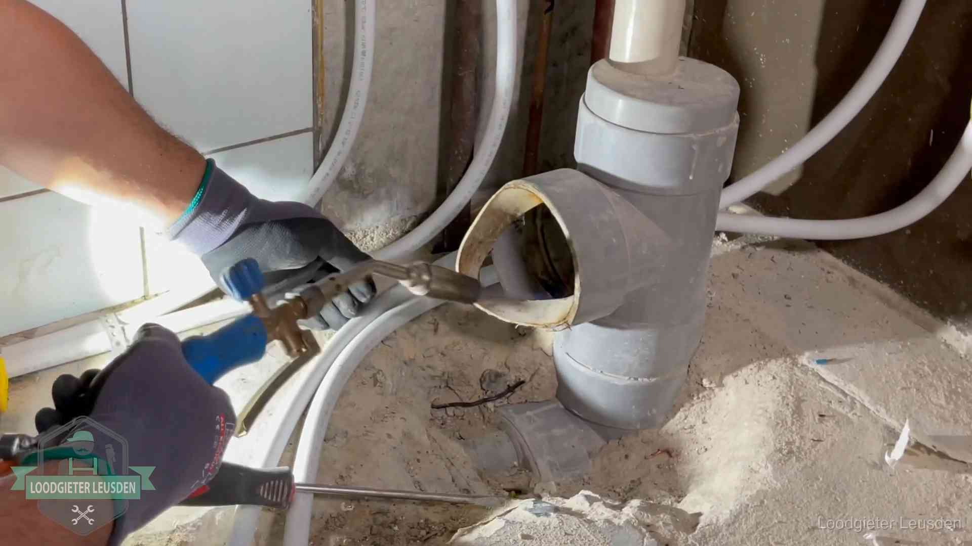 Loodgieter werkt met brander en messing kraanwerk aan leidingen in Leusden