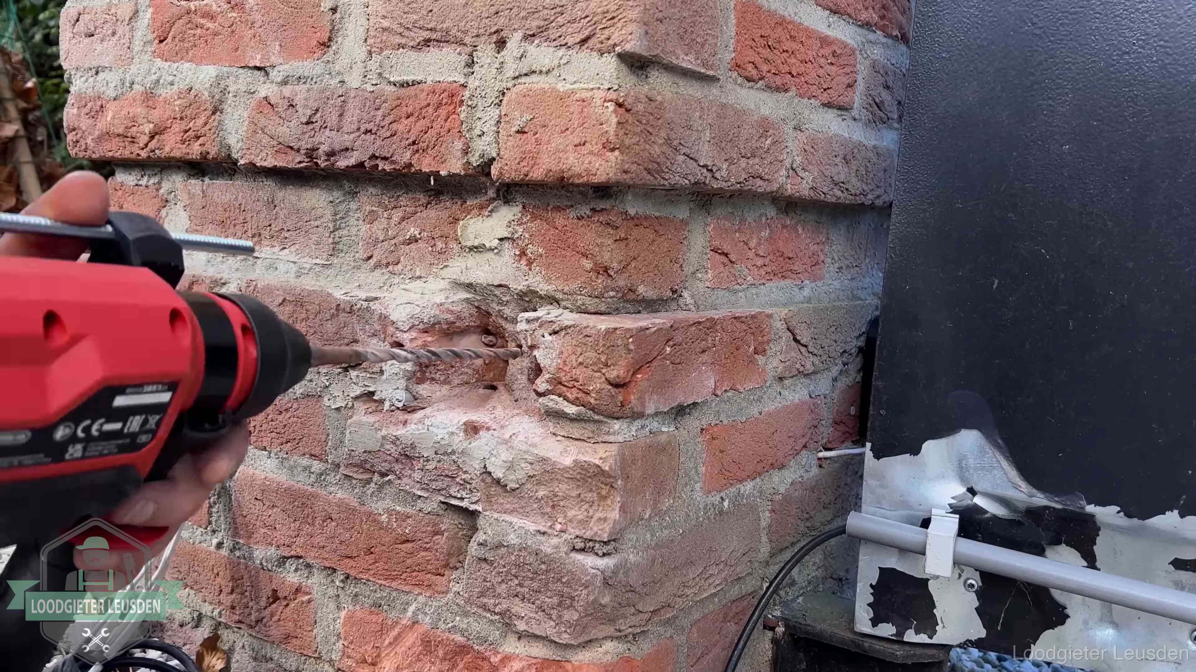 Vakman boort in de buitenmuur van een woning in de regio Leusden