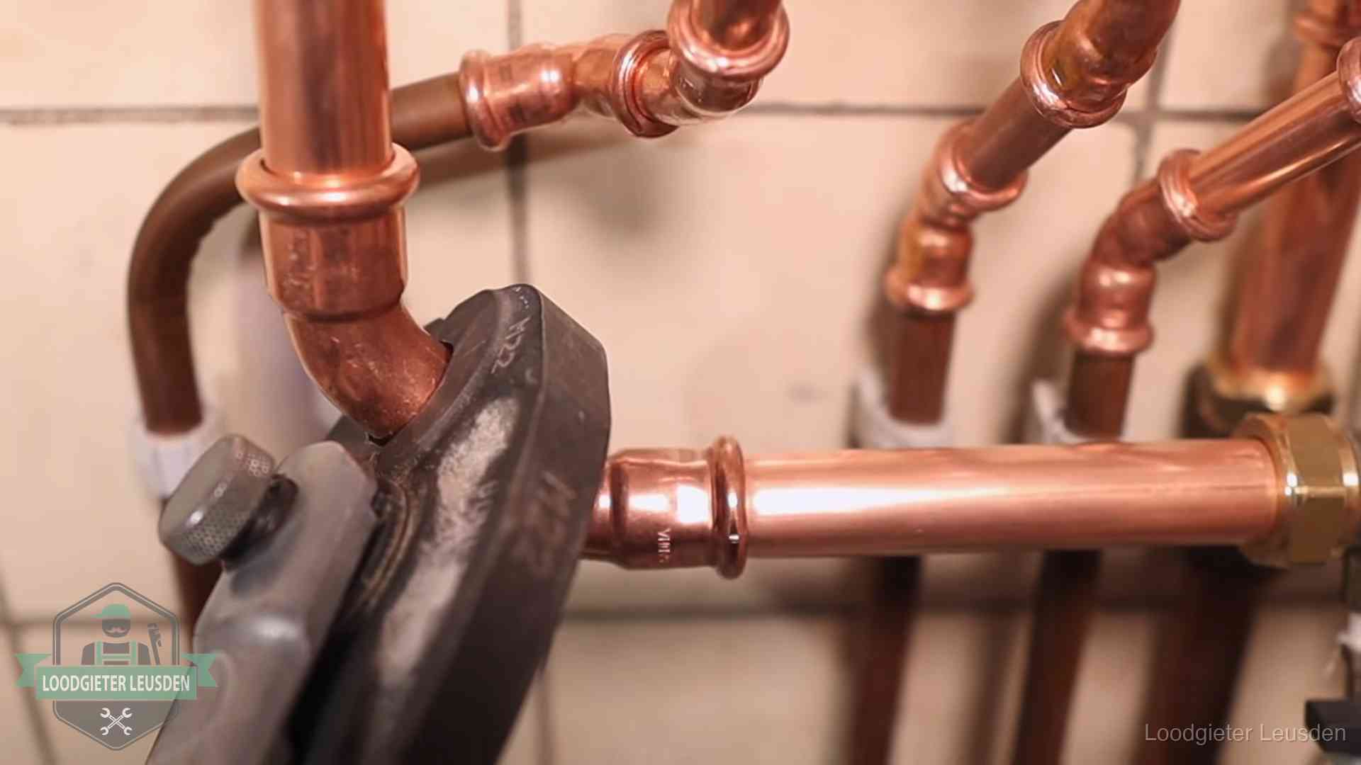 Persmachine perst een koperen fitting op nieuw leidingwerk in Leusden