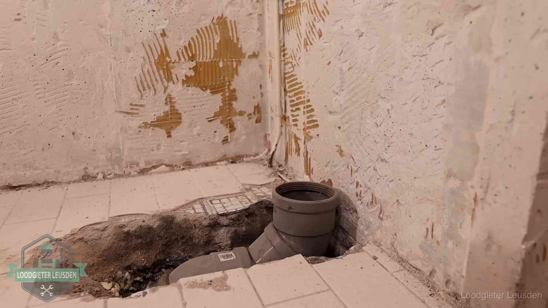 Opengebroken vloer met een nieuwe pvc-rioolbocht in een gegraven sleuf in Leusden