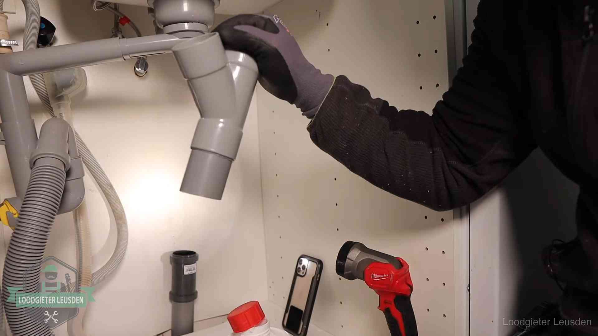 Loodgieter demonteert het sifon- en afvoerwerk onder een gootsteen in Leusden bij stankklachten