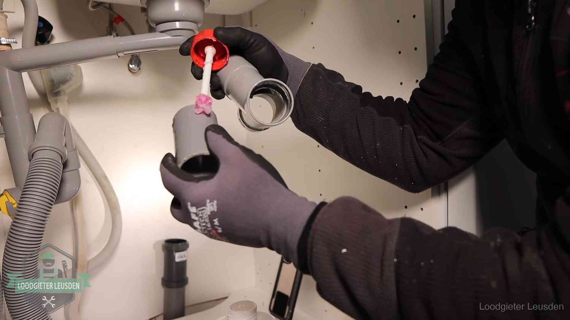 Loodgieter demonteert en reinigt de sifon onder een keukenkast in Leusden